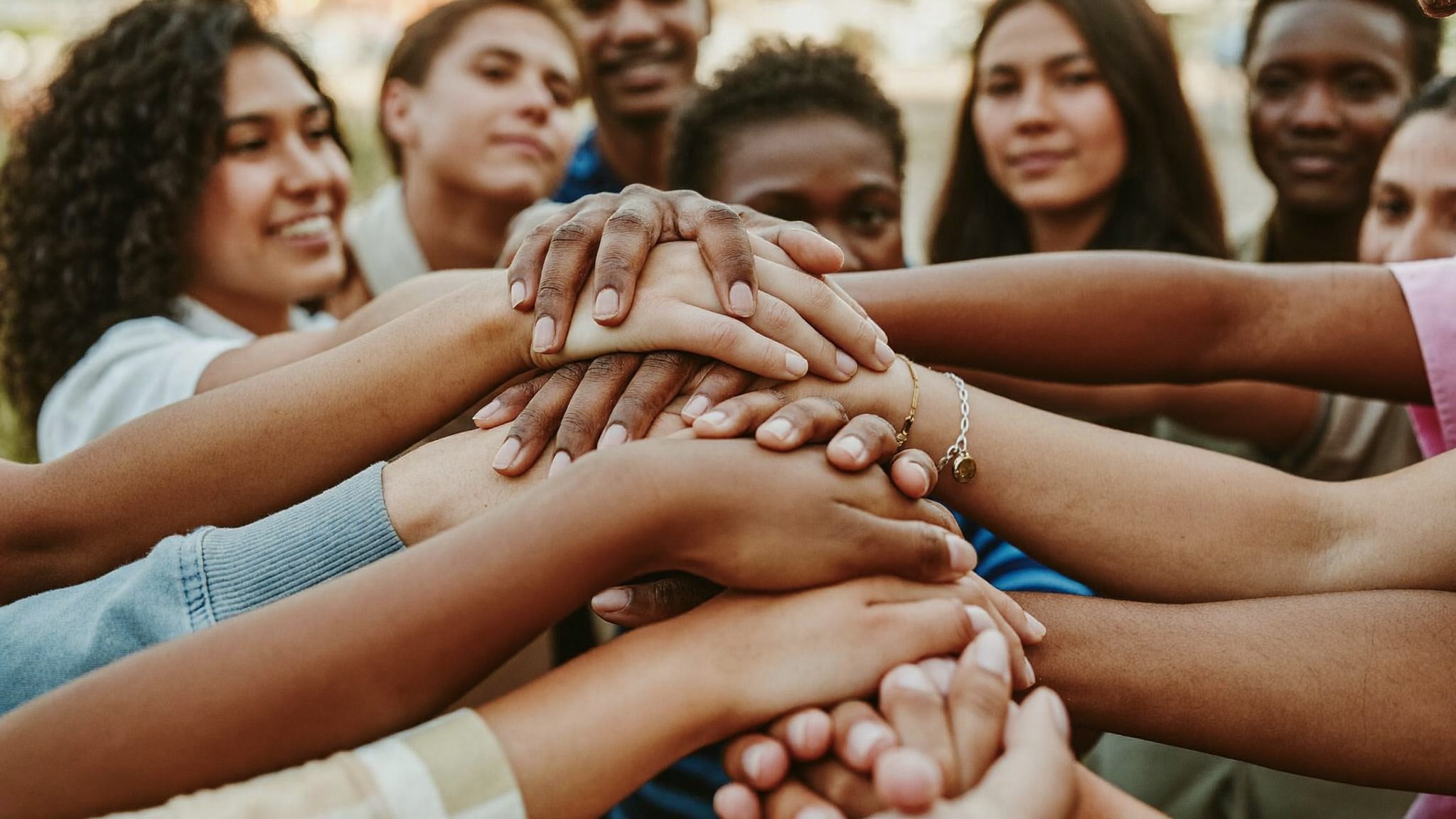 Diverse hands clasped together, representing collaboration between organizations and the community.